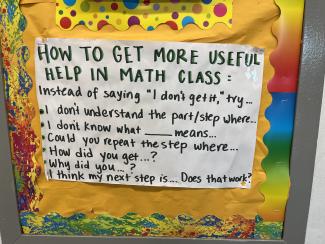 Vor farbenfrohem Hintergrund listet ein Poster im Klassenzimmer mit dem Titel „Hot to get more useful help in math class“ Tipps für Schüler:innen.