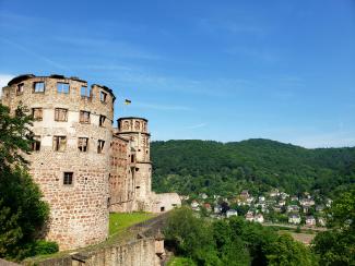 Turm des Heidelberger Schlosses vor blauem Himmel mit Blick auf das bewaldete Tal | Steven He / Unsplash