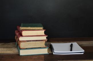 Bücherstapel mit Notizblock und Stift