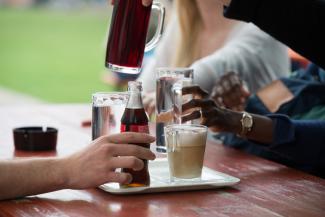 Bierbank im Außenbereich der Mensa mit Tablett und Getränken