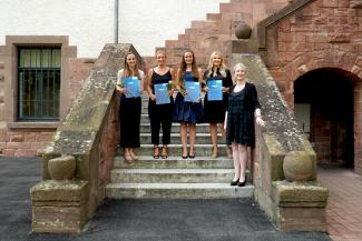 Die vier Preisträgerinnen stehen – gemeinsam mit Vera Heyl – auf der Treppe, die vom Innenhof in den Altbau der PH führt, und halten ihre Urkunden sowie Blumen in der Hand.