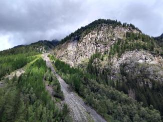 Ein steiniger Pfad führt durch den Wald auf einen Berggipfel