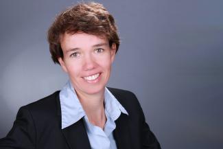 Porträt von Prof. Dr. Claudia Hildebrandt vor grauem Hintergrund. Bild: privat