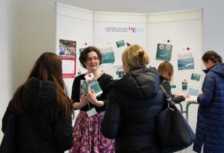 Eine HSE-Mitarbeiterin mit Flyern in der Hand berät am Infostand Lehramtsinteressierte.