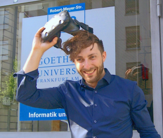 Prof. Dr. Andreas Dengel zieht sich eine VR-Brille vom Kopf, im Hintergrund ein Schild der Goethe-Universität.