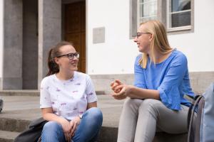 Zwei Studentinnen sitzen auf der Treppe vor der Neuen Universität Heidelberg