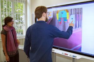 Junge Frau und junger Mann interagieren mit Smartboard