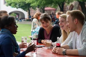 Studierende sitzen im Marstallhof der Universität Heidelberg zusammen
