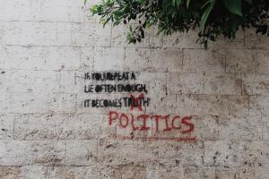 Graffitti auf einer Mauer mit dem Text: „If you repeat a lie often enough it becomes truth“. Das Wort „truth“ ist durchgestrichen und durch „politics“ ersetzt. 