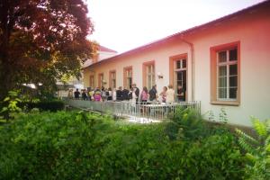 Das Bild zeigt viele Menschen im Gespräch auf der HSE-Terrasse im Abendrot, umgeben von Baum und Büschen.