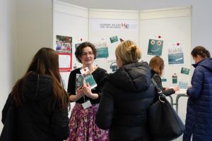 Eine HSE-Mitarbeiterin mit Flyern in der Hand berät am Infostand Lehramtsinteressierte.