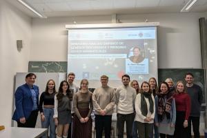 Gruppenbild mit Prof. Dr. René Venegas, Prof. Dr. Sibylle Große und Studierenden des Romanischen Seminars. Auf der Leinwand im Hintergrund der Vortragstitel „Análisis empírico de géneros discursivos y patrones léxico-gramaticales“