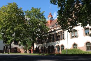 Das Bild zeigt den Altbau der Pädagogischen Hochschule Heidelberg, umgeben von Bäumen.