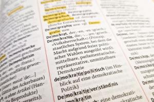 Das Bild zeigt die aufgeschlagene Seite eines Lexikons mit der Definition von Demokratie. 