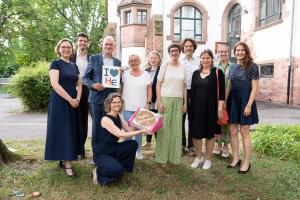 Gruppenfoto mit Prof. Dr. Marita Friesen, Dr. Sebastian Mahner, Dr. Hans J. Reter, Theresia Bauer, Prof. Dr. Petra Deger, Prof. Dr. Frauke Melchior, Prof. Dr. Beatrix Busse, Prof. Dr. Silke Hertel und Dr. Christiane Wienand mit HSE-Jubiläumstorte und "I love HSE"-Schild
