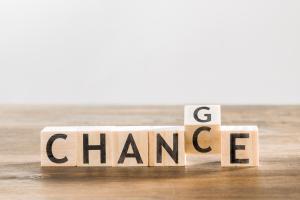 Buchstabenwürfel aus Holz bilden das Wort CHANCE. Das C ist gedreht, sodass auf der angrenzenden Seite ein G zu sehen ist. Botschaft: Change = Chance.