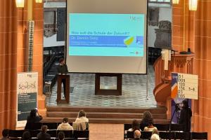 Dr. Dennis Dietz bei seinem Vortrag in der Akademischen Mittagspause am Pult der Peterskirche. Hinter ihm die Vortragsfolie..