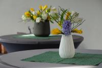 Auf Stehtischen sind Hyazinthen, Tulpen und Narzissen als frühlingshafte Dekoration in Vasen arrangiert.