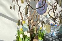 In einem Osterkorb mit Tulpen, Narzissen und Hyazinthen hängen selbst bemalte und beschriftete Ostereier aus Holz an einem Osterstrauch.
