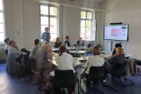 Beirat und Direktorium der HSE bei der konstituierenden Sitzung im Konferenzraum. Die Tische sind in U-Form angeordnet, rechts im Bild ein Smartboard, das eine Folie zum Thema Future Literacies zeigt.