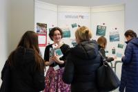 Eine HSE-Mitarbeiterin mit Flyern in der Hand berät am Infostand Lehramtsinteressierte.