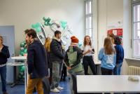 Eine Lehramtsstudierende im HSE-Shirt im Gespräch mit Abiturient:innen, im Hintergrund große HSE-Ballons in Silber und Mint.