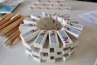 Radiergummis und Bleistifte mit HSE-Logo sowie weiterer Merchandise sind auf einem Tisch zum Mitnehmen ausgelegt.