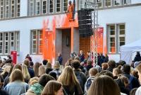 Studierende am Willkommenstag auf dem Uniplatz, im Hintergrund die von der Letzten Generation orange mit Farbe beschmierte Neue Universität.