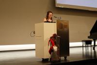 Rebecca Louise Smith bei ihrem Poetry Slam auf der Bühne der Neuen Aula. Vor dem Pult ein Weihnachtswichtel, an einer Laterne lehnend.
