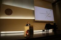 Dr. Dennis Dietz bei seinem Fachvortrag „Wertvolle Freiheit. Über Verantwortung und Vertrauen im Schulberuf“ am Rednerpult. Neben ihm eine Grafik auf der Leinwand, die persönliche, sachliche und pädagogische Herausforderungen im Lehrer:innenberuf illustriert..