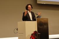 Prof. Dr. Michael Haus bei seiner Ansprache an die Absolvent:innen gestikulierend am Rednerpult.