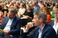 Prof. Dr. Jörg Peltzer in nachdenklicher Haltung im Publikum, hinter und neben ihm weitere Gäste