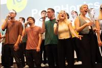 Mitglieder der PolyPhonics singen in ihre Mikrofone