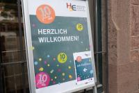 Ein Plakataufsteller mit dem Schriftzug HERZLICH WILLKOMMEN und buntem Konfetti weist den Weg zum Festakt.