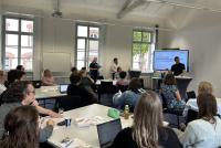 Teilnehmende des Zukunftsforums sitzen an Tischen gruppiert im KOnferenzraum der HSE. Am Smartboard stehen Dr. Dennis Dietz, Dr. Daniel Vetter und Dr. Lina Pranaityte