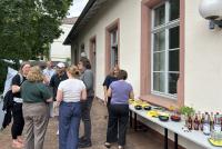 Auf der belaubten Terrasse der HSE tauschen sich die Teilnehmenden des Zukunftsforums aus. Rechts im Bild ein kleines Buffet aus Käsewürfeln, Trauben, Crackern und Limonaden.