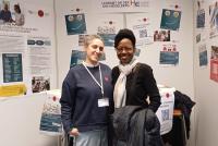 Margherita Maulella (links) und Dr. Portia Williams (rechts) am Infostand der HSE, im Hintergrund HSE-Plakate.