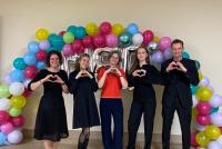 Das Team des HSE-Prüfungsamts vor dem Ballonbogen. Alle formen mit den Händen ein Herz.