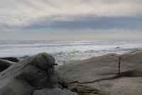 Graue, glatte Felsen am Meer unter bewölktem Himmel