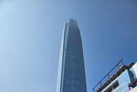 Der Wolkenkratzer "Gran Torre Santiago" ragt in den blauen Himmel. Im Vordergrund die Stadt.