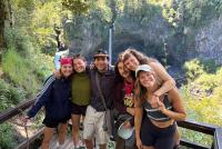 Studierende beim Wandern vor Bäumen und einem Wasserfall in der Region Araukarien