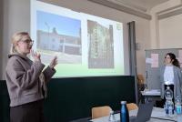 Marieke Onnasch und Birte Böhmer bei ihrem Vortrag zur Ernst-Reuter-Schule. Auf der Leinwand ein schickes Einfamilienhaus neben einem Sozialwohnungsbau.