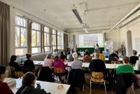 Ein voll besetzter Seminarraum; vorne präsentieren Birte Böhmer und Marieke Onnasch das Konzept der Ernst-Reuter-Schule.