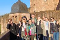 Die Teilnehmenden der Staff Week auf der Terrasse des Heidelberger Schlosses unter blauem Himmel. Im Hintergrund der Turm.