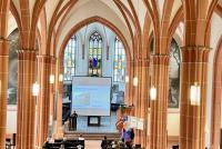 Blick von oben auf das gut gefüllte Kirchenschiff der Peterskirche beim Vortrag von Theresa Heyd.