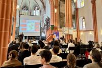 Blick über die Köpfe des zahlreich zu Theresa Heyds Vortrag erschienenen Publikums auf die Referentin und ihre Vortragsfolien in der Peterskirche.