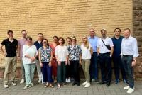 Gruppenbild von 14 Mitgliedern der AG Querschnittskompetenzen vor einer Mauer